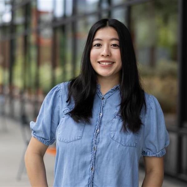Jada smiling while wearing a jean shirt and standing outside of Obsidian Hall on the OSU Cascades campus.
